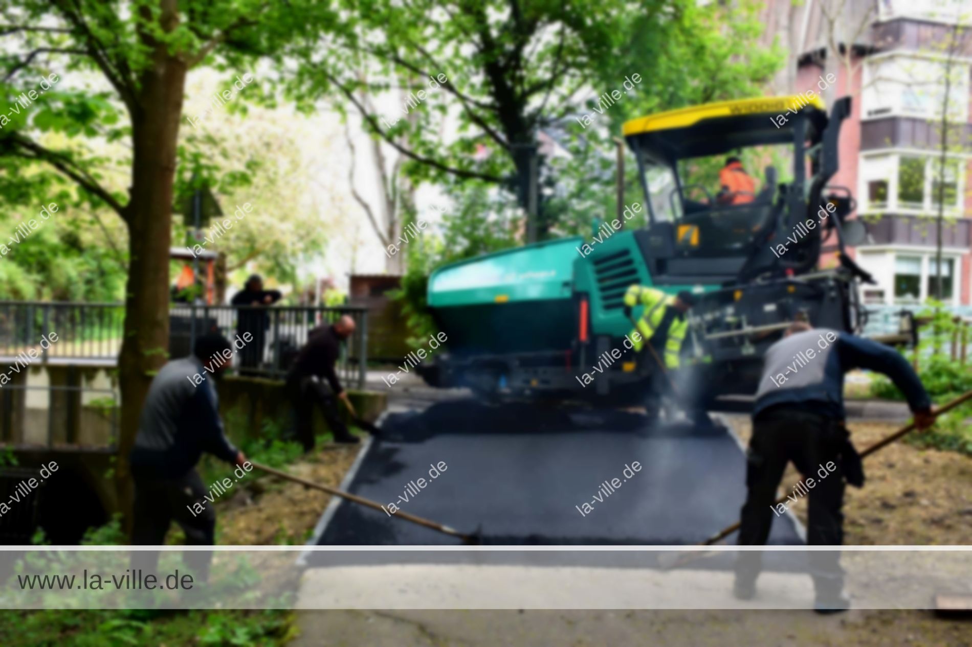Eine Gruppe von Arbeitern verlegt Asphalt auf eine Straße.