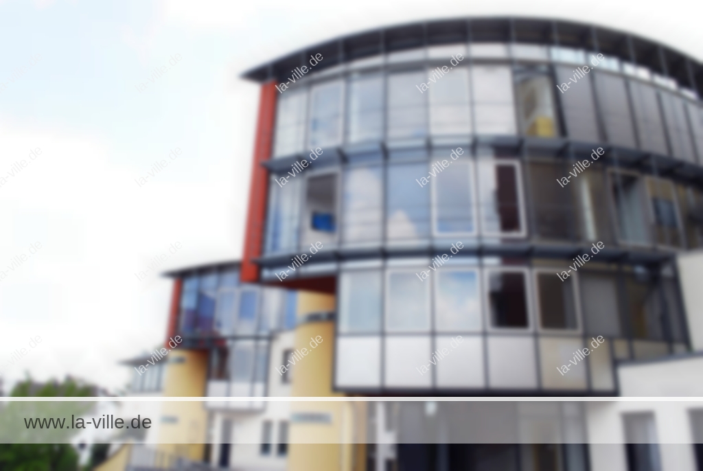 Ein modernes, mehrstöckiges Gebäude aus Glas und Stahl mit geschwungener Architektur, dargestellt in einem unscharfen Bild.